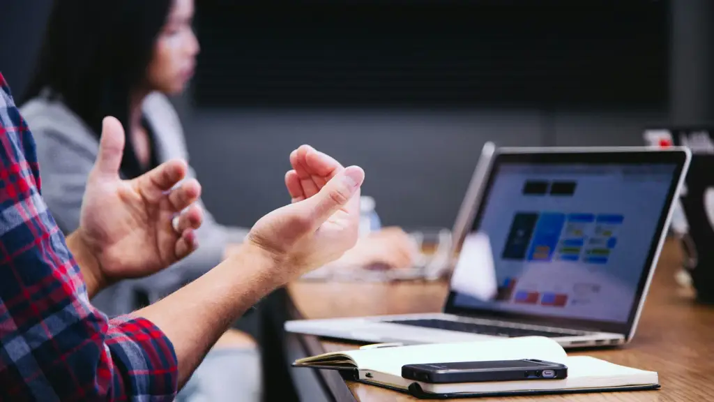 Two people talking across a laptop in a meeting