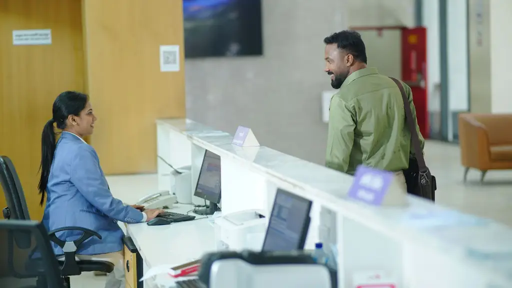 A receptionist and a visitor at a hospital front desk