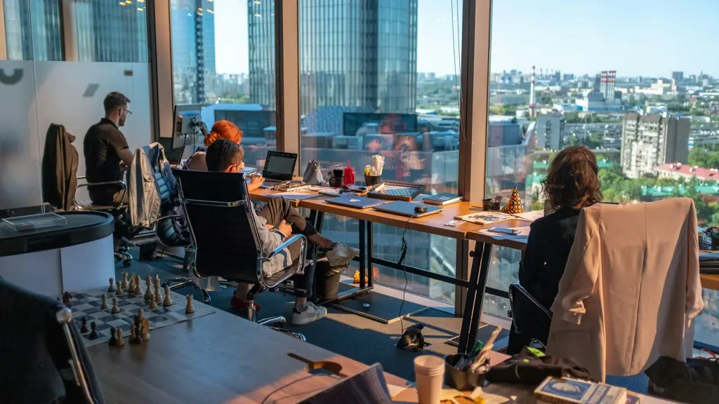 An open-plan office with desks facing a city skyline