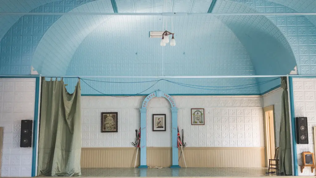 An empty village hall with a small stage and pale blue walls