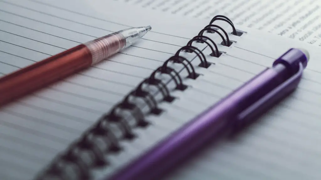 A blank spiral-bound notebook with two pens resting on it