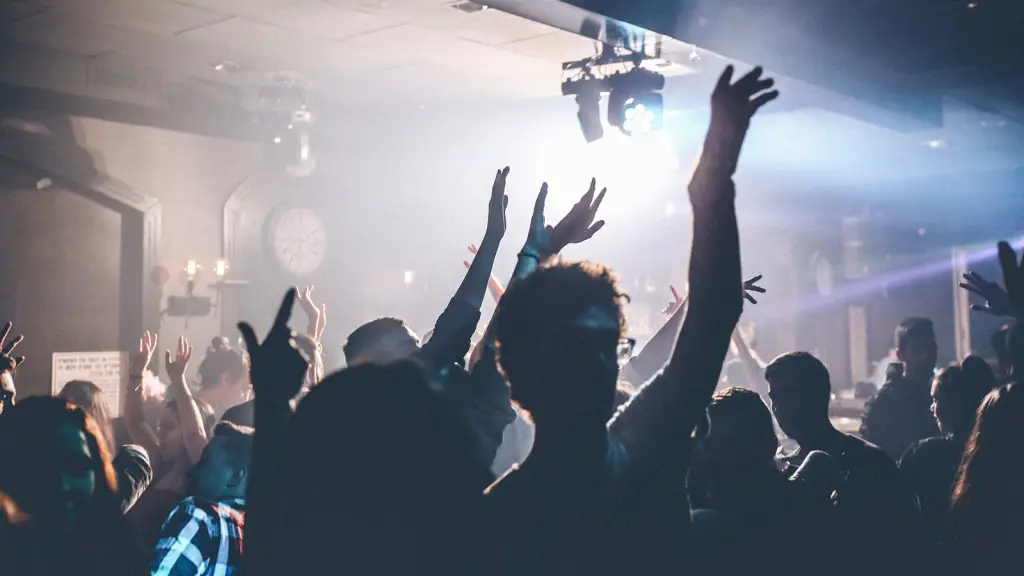A nightclub crowd with hands raised under stage lighting