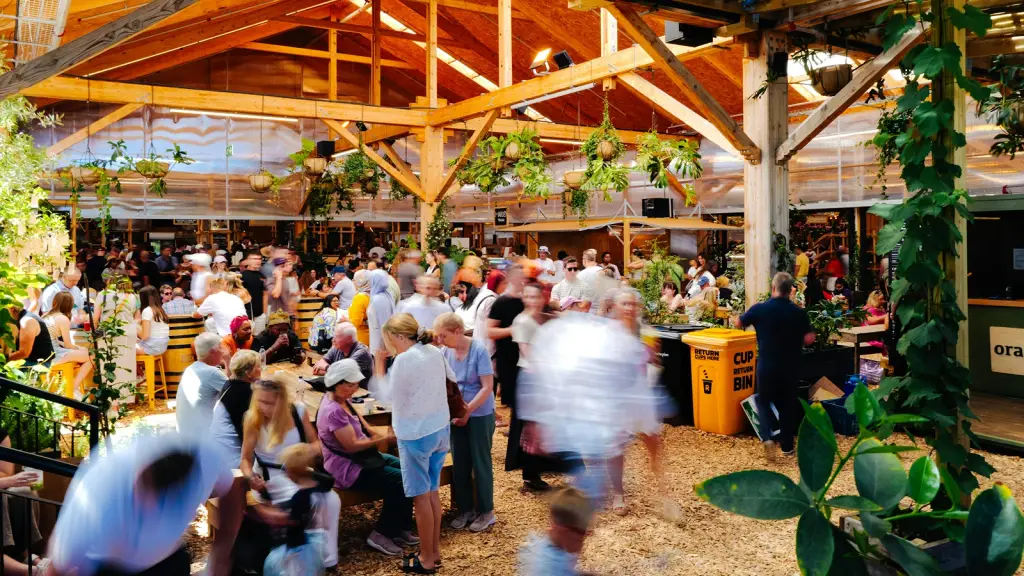A crowd moving through a covered market hall with a timber roof