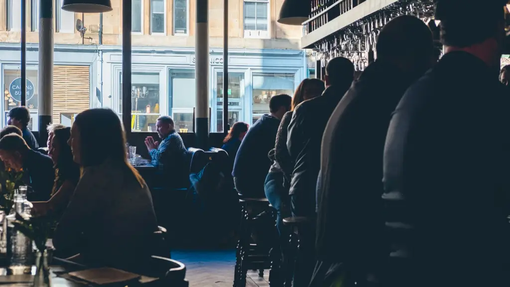 Drinkers silhouetted along a pub bar against a bright window