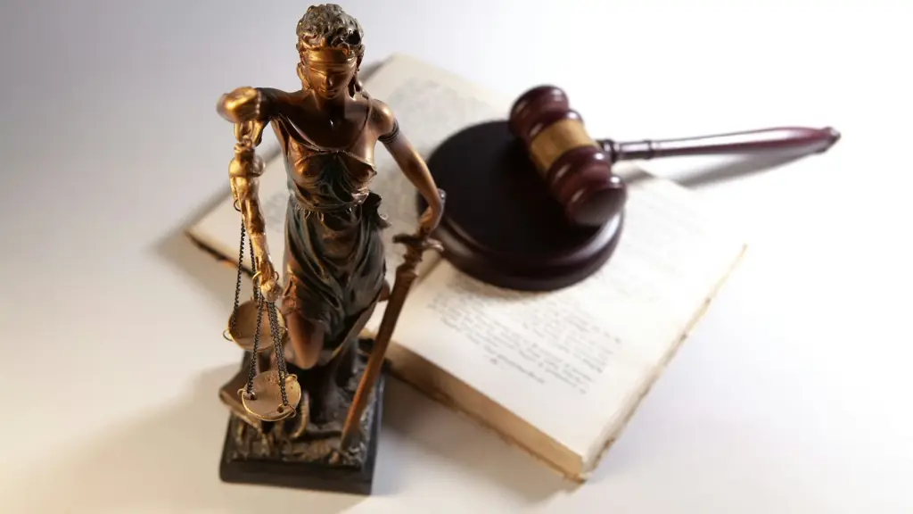A brass figure of Lady Justice and a gavel resting on an open book